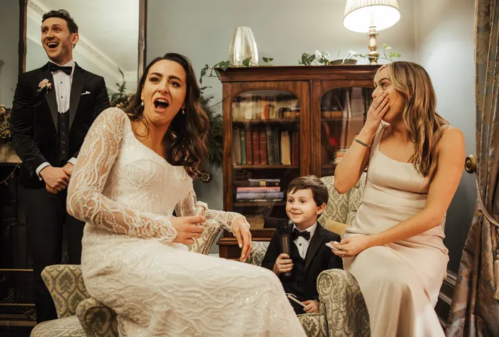 A bride laughing on a sofa with her family around her