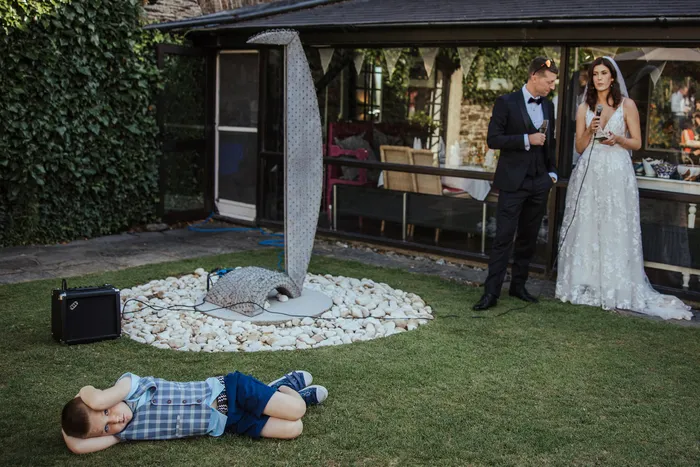 A couple by a garden room while a child lies on the grass