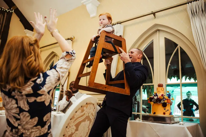 Guests lifting a man on a chair, hands in the air