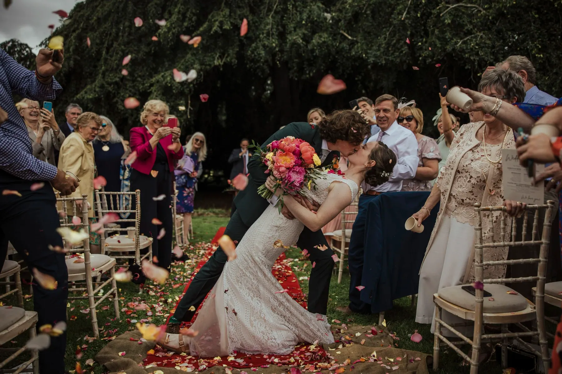 Guests throwing confetti over a couple in a garden
